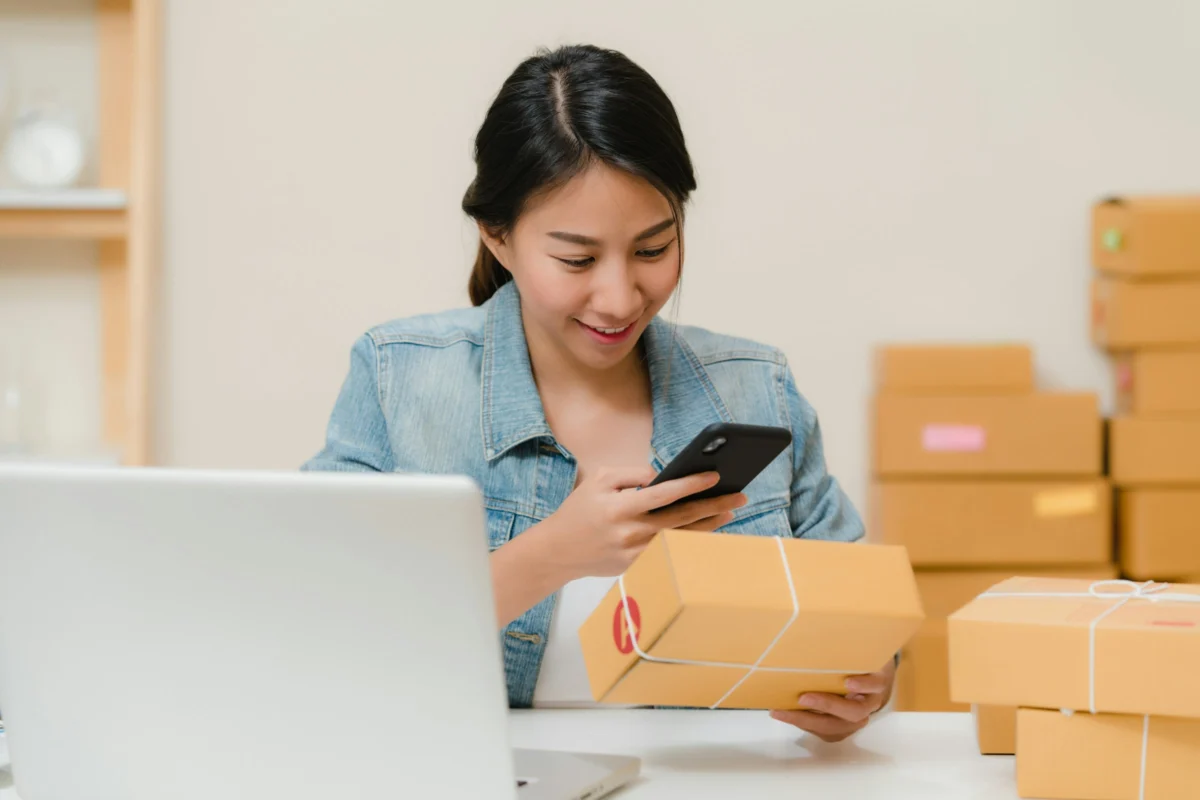 Ecommerce & shopify seo services 1 Online shop owner checking an order beside her laptop and parcels, the kind of store our ecommerce SEO helps