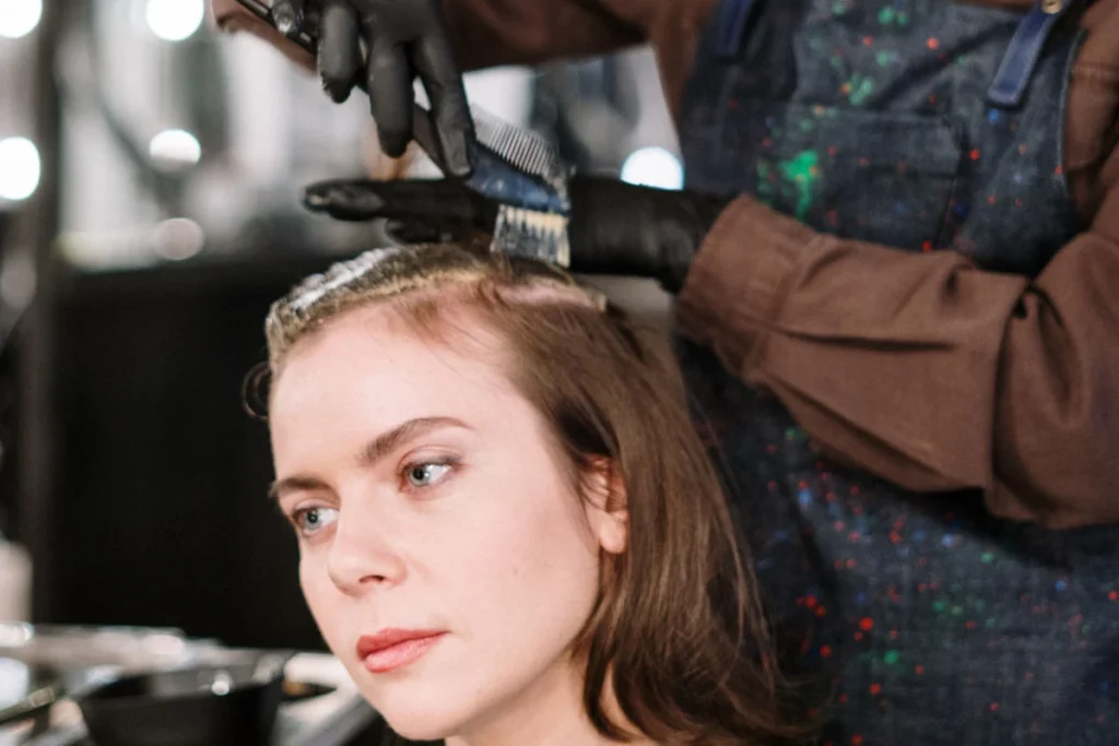Stylist colouring a client's hair in a salon, the kind of booking a monthly Instagram ad budget aims to win