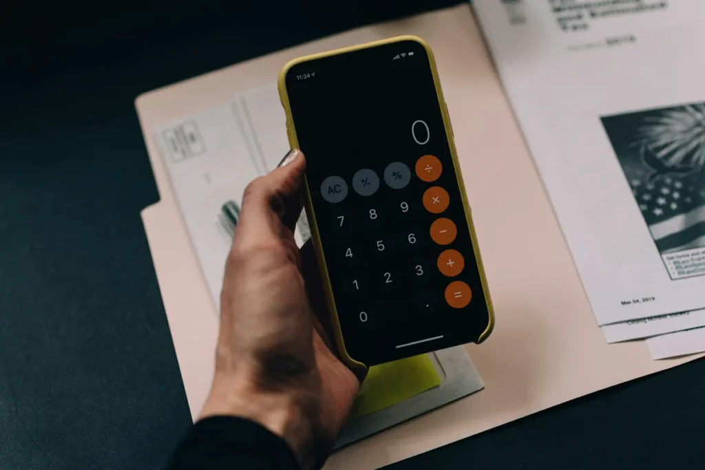 Hand holding a phone calculator over a paper folder while working out a small business SEO budget