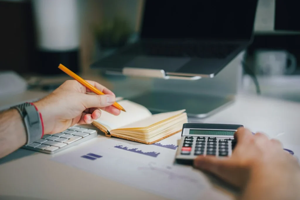 Seo vs google ads: which is better for a small business? 1 Calculator and notebook on a desk while working out a monthly budget for SEO and Google Ads